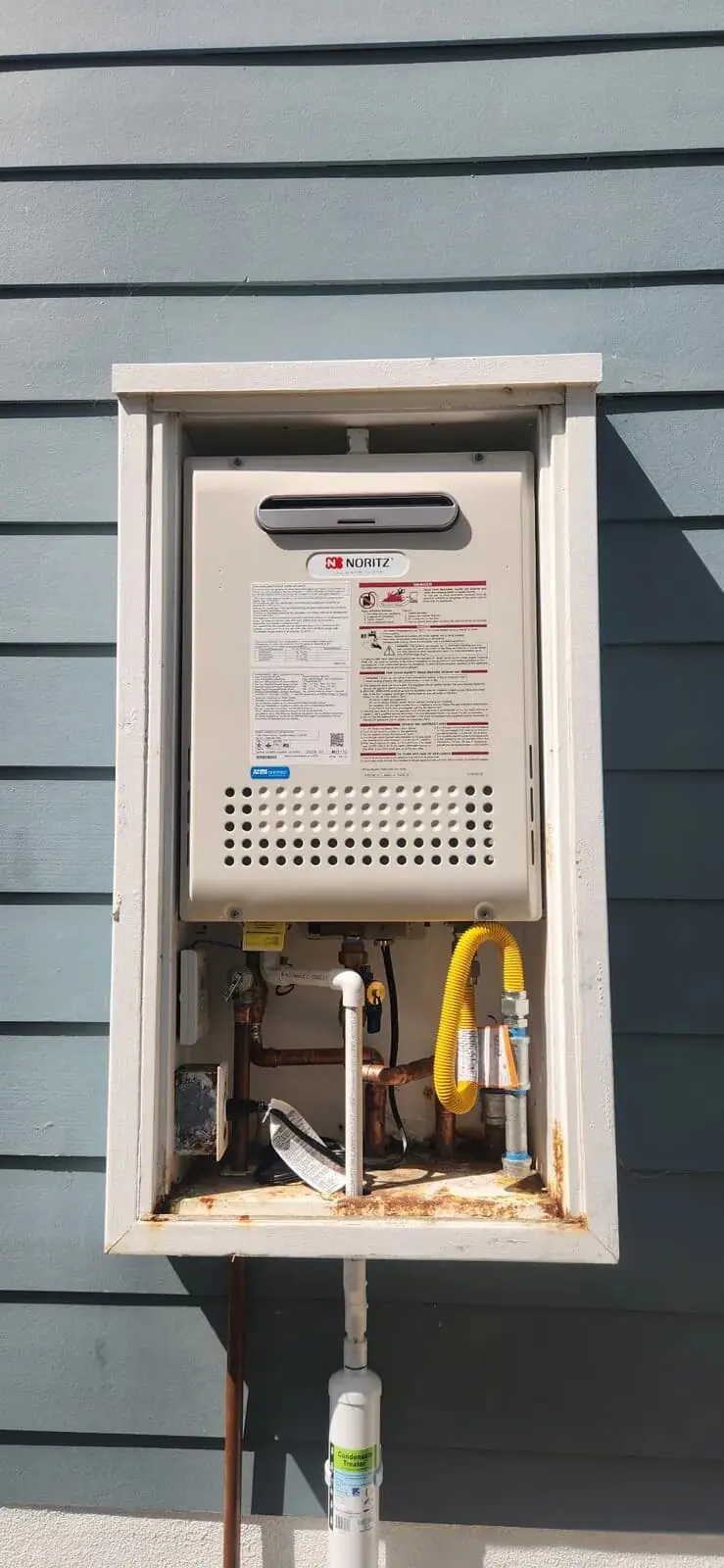 Exterior mounted tankless water heater on home siding