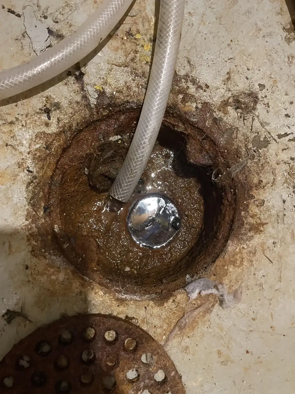 Rusted floor drain set into a concrete slab floor
