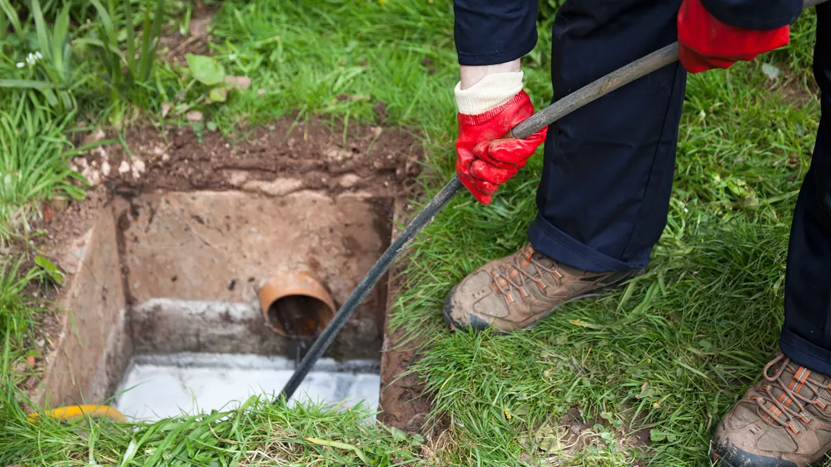Technician feeding a jetting hose into a sewer line access point