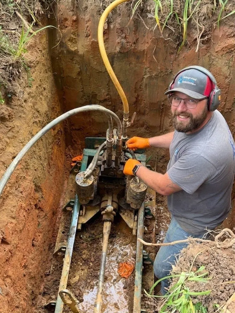 Plumber repairing a sewer pipe inside a narrow excavation trench